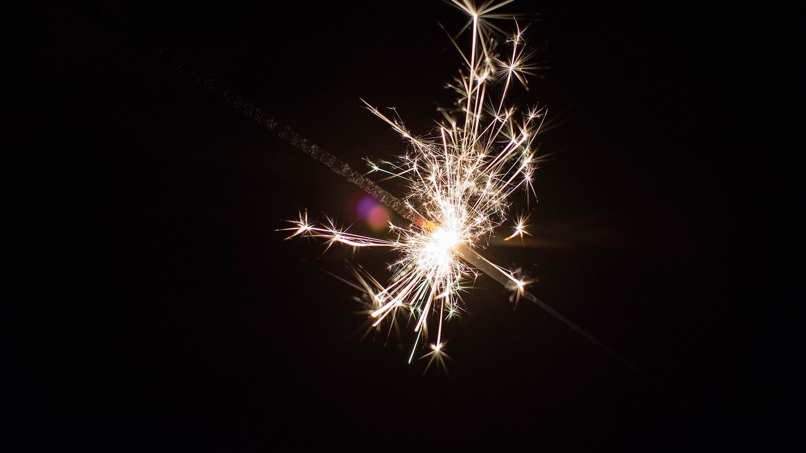 Étincelles dorées tenues à la main pendant une soirée du Nouvel An